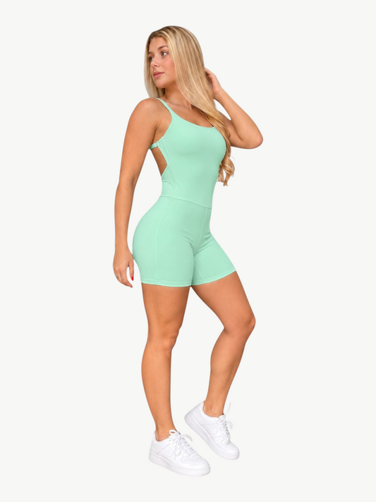 A woman wearing a mint green JM Brazilian Activewear Sculpt Romper with a low back design and fitted shorts.