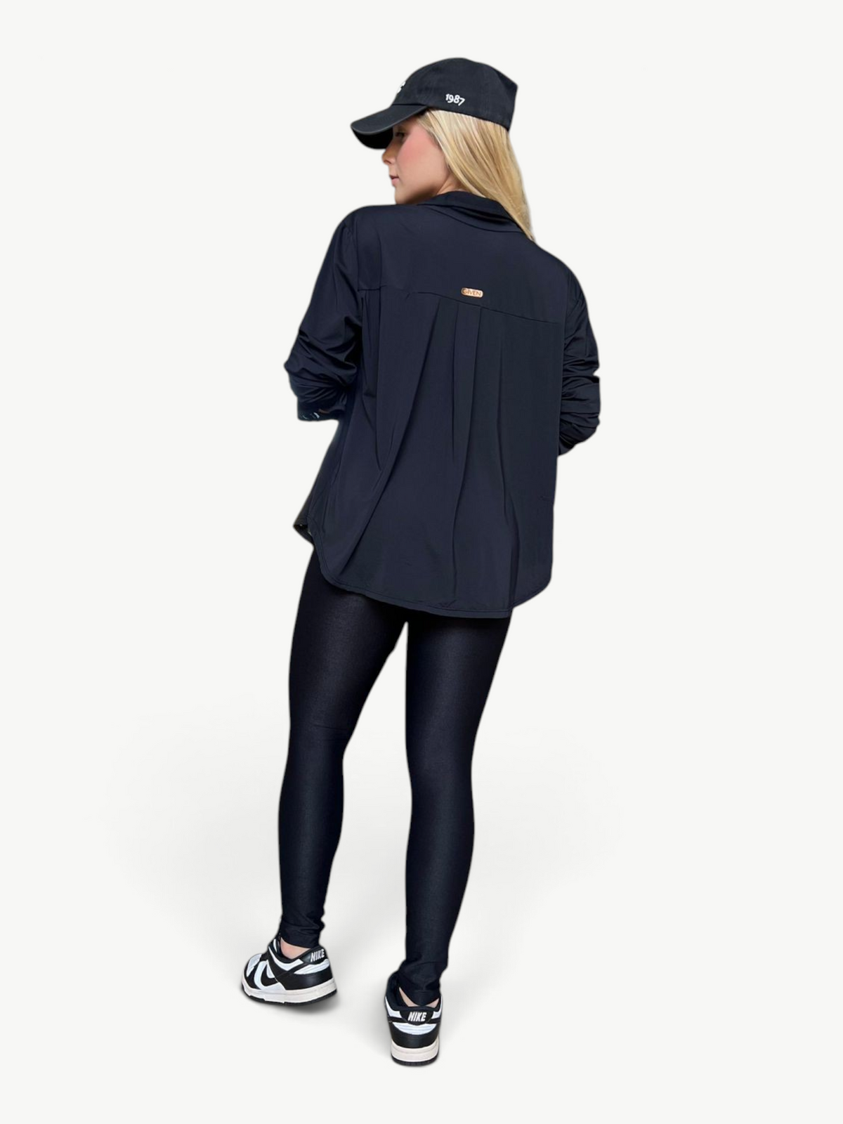 Model wearing a black JM Brazilian Activewear long sleeve button-up top with a pleated back and matching leggings.