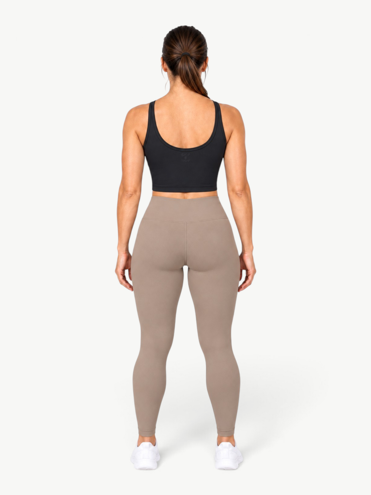 Back view of a woman wearing a JM Brazilian Activewear black Dallas crop top and taupe leggings