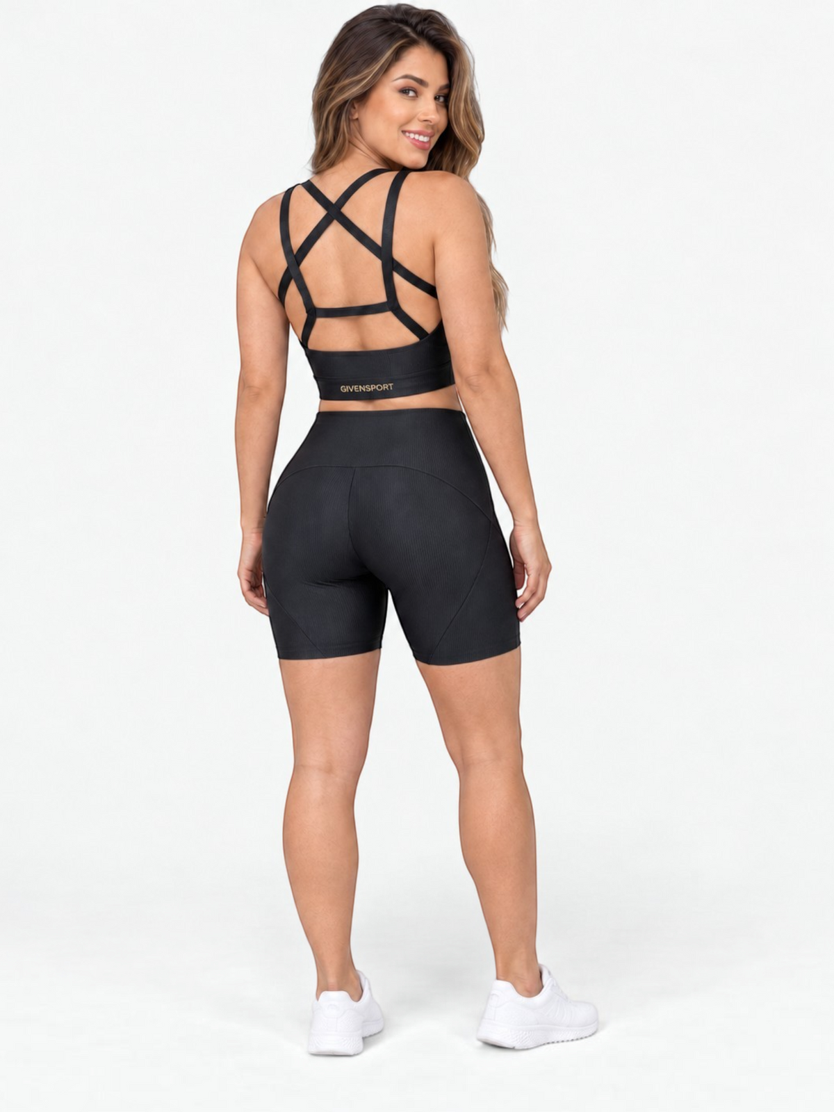 JM Brazilian Activewear black crossback crop top and high-waisted biker shorts set worn by a woman from behind