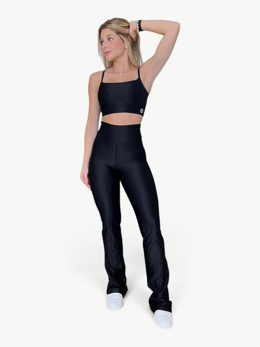 Model wearing a black JM Brazilian Activewear two-piece set with a fitted crop top and high-waisted flare pants.