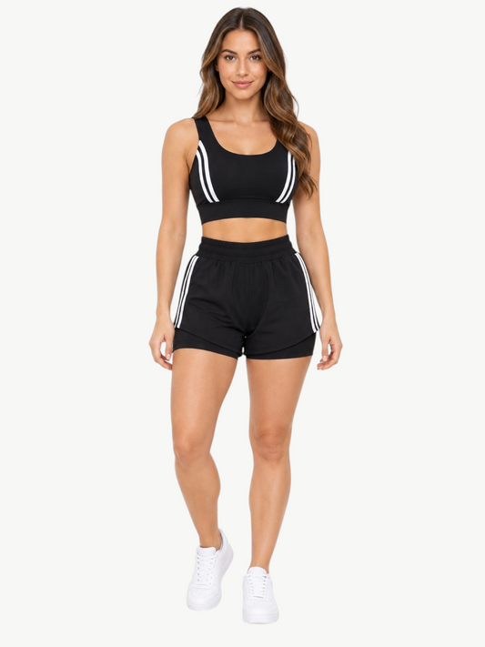 Model wearing a black JM Brazilian Activewear 2-in-1 short set with white stripe details on the crop top and shorts.