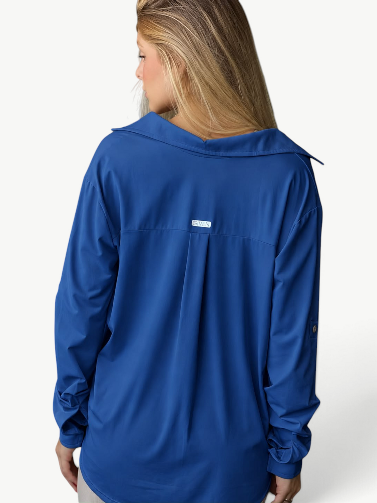 Woman wearing a royal blue JM Brazilian Activewear long sleeve button-up top with a back pleat and logo detail