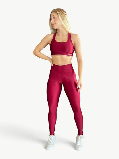 Model wearing a JM Brazilian Activewear burgundy cropped top and high-rise leggings set with contrast detailing.