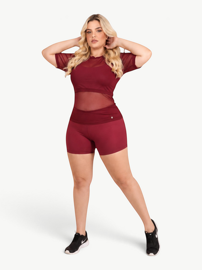 Model wearing a JM Brazilian Activewear burgundy sheer mesh t-shirt over a matching sports bra and shorts