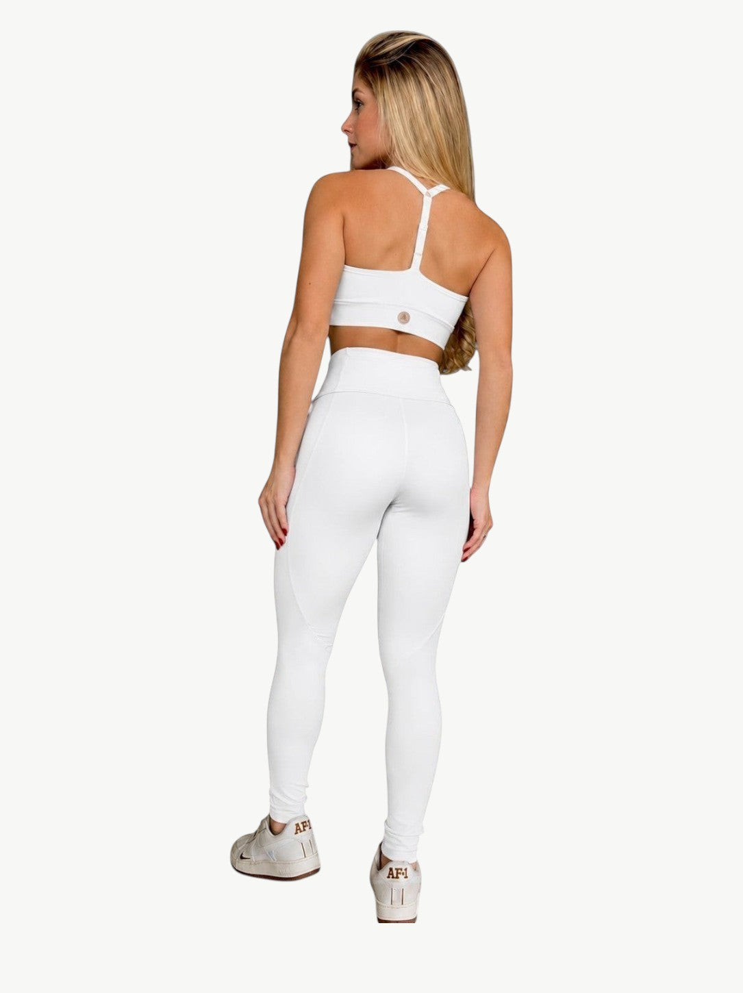 Modelo de costas vestindo conjunto de legging e top cropped branco da JM Brazilian Activewear para treino.