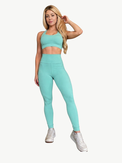 Modelo loira vestindo conjunto de legging e top cropped verde-água da JM Brazilian Activewear para treino.