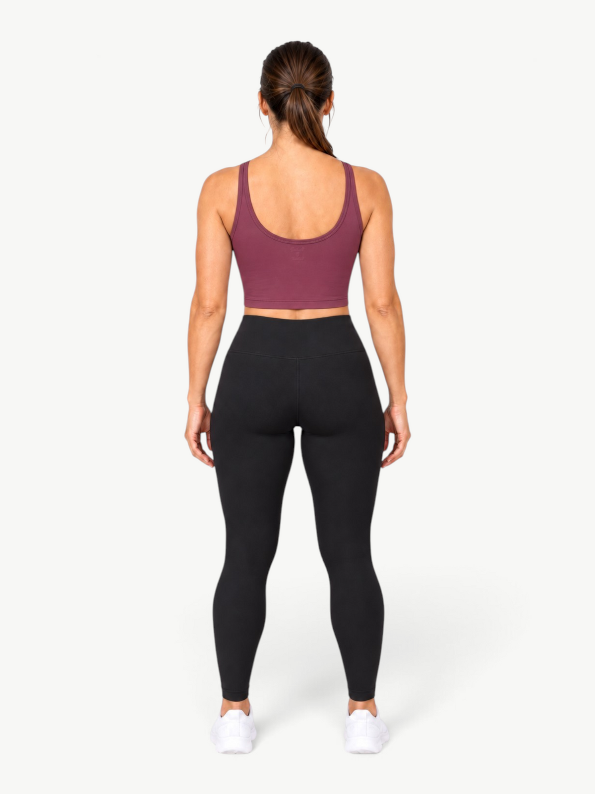 Back view of a woman wearing a JM Brazilian Activewear Dallas Crop Top in deep plum with black leggings