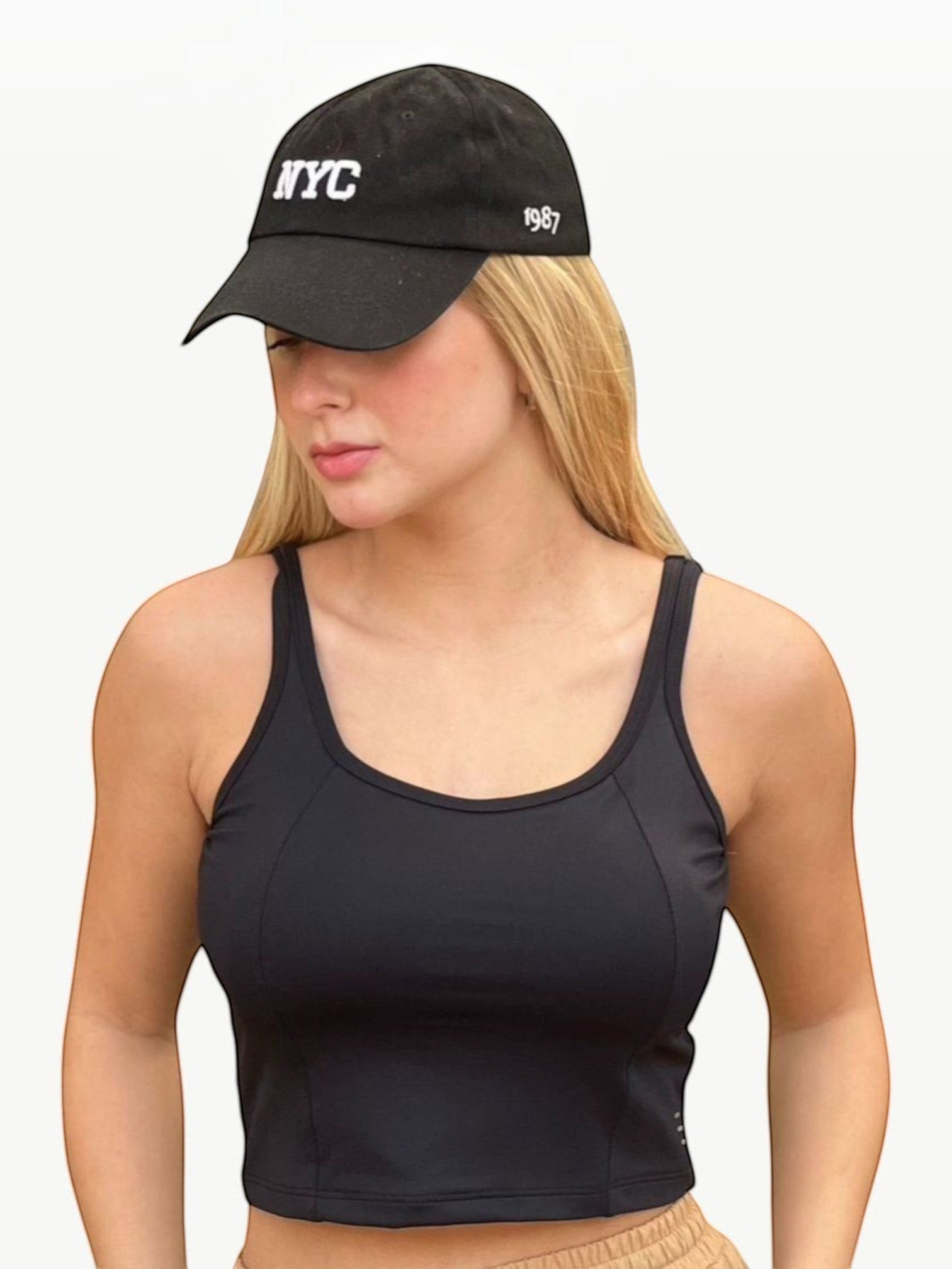 Modelo loira vestindo o Dallas Crop Top preto da JM Brazilian Activewear com boné preto estilo casual