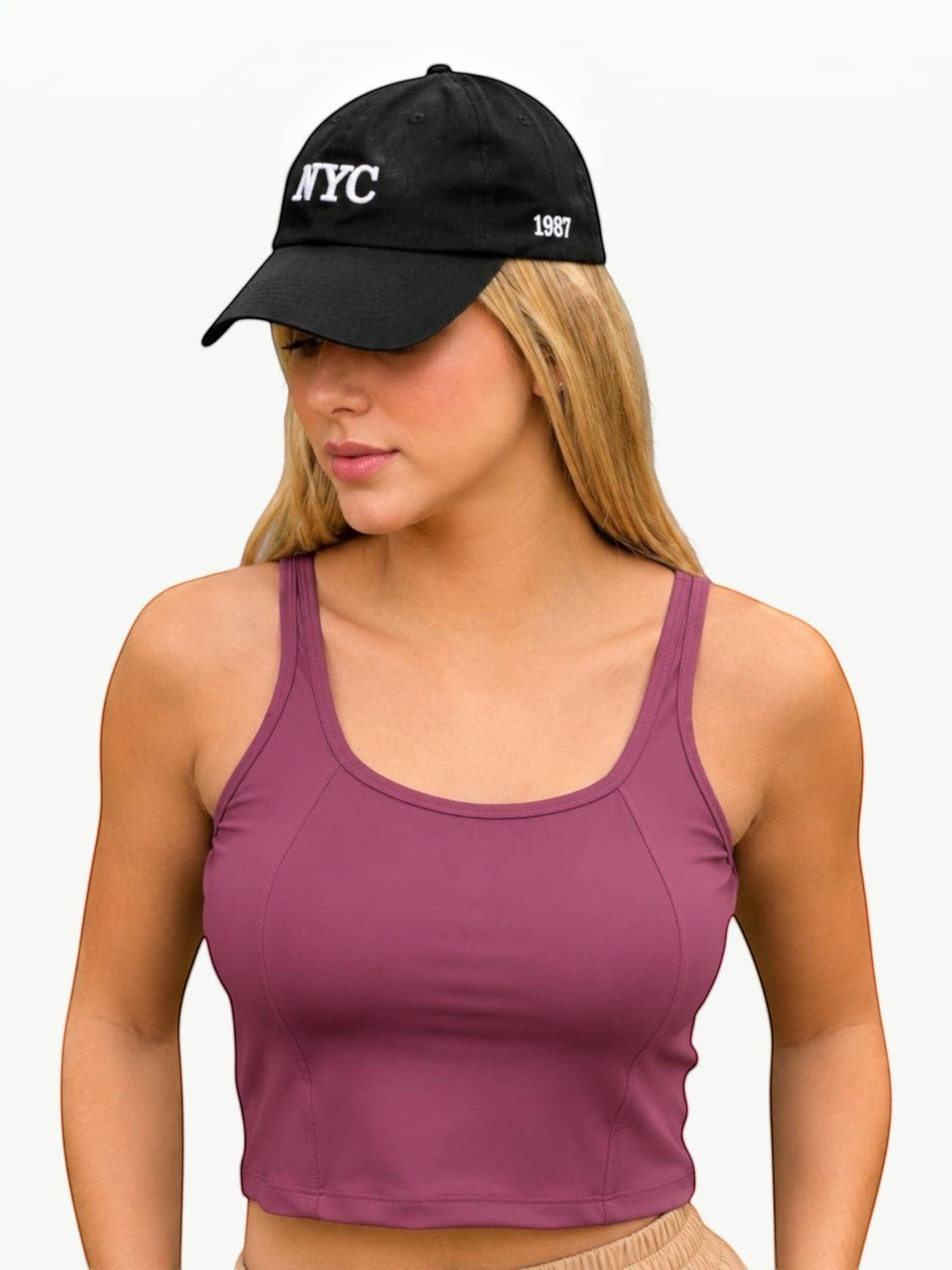 Modelo vestindo Dallas Crop Top roxo da JM Brazilian Activewear com boné preto NYC em fundo branco