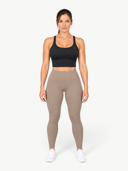Model wearing a black JM Brazilian Activewear Dallas crop top with taupe leggings and white sneakers