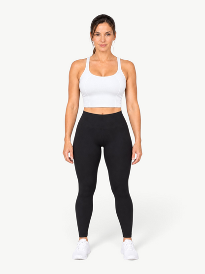Model wearing a white JM Brazilian Activewear Dallas crop top with black leggings and white sneakers