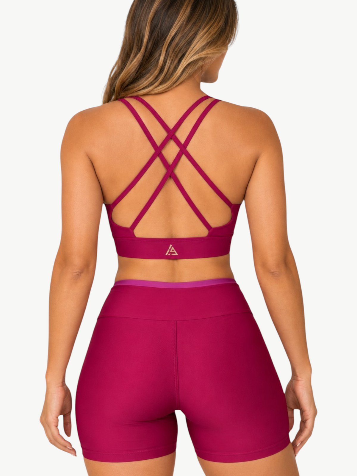 Model wearing JM Brazilian Activewear Aurora Short Set in deep magenta with a strappy back crop top and high-waist
