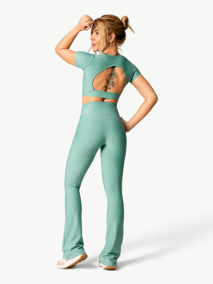 JM Brazilian Activewear mint green short-sleeve crop top and high-waisted flare pants set worn by a woman from behind