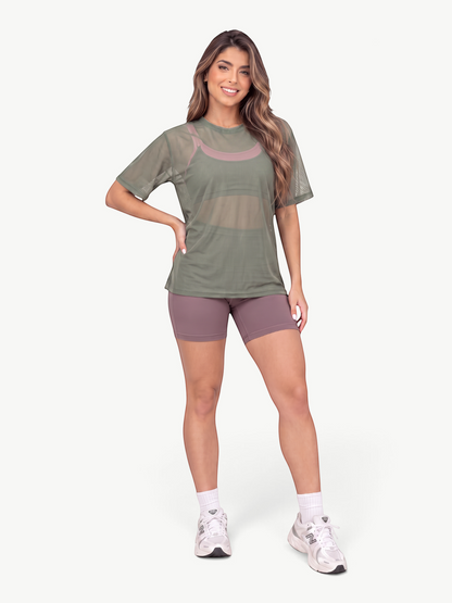Model wearing a JM Brazilian Activewear olive green sheer mesh t-shirt over a mauve sports bra and matching shorts.