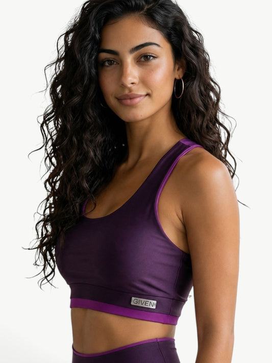 JM Brazilian Activewear purple cropped sports bra with contrast trim worn by a woman with long curly hair
