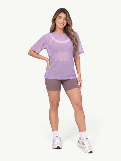 Model wearing a JM Brazilian Activewear purple sheer mesh t-shirt over a sports bra with matching athletic shorts
