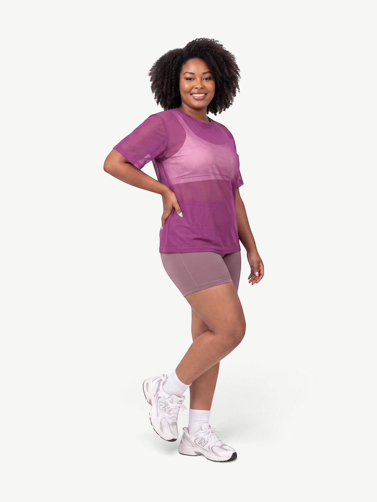 Model wearing a JM Brazilian Activewear purple sheer mesh t-shirt over a matching sports bra and athletic shorts.