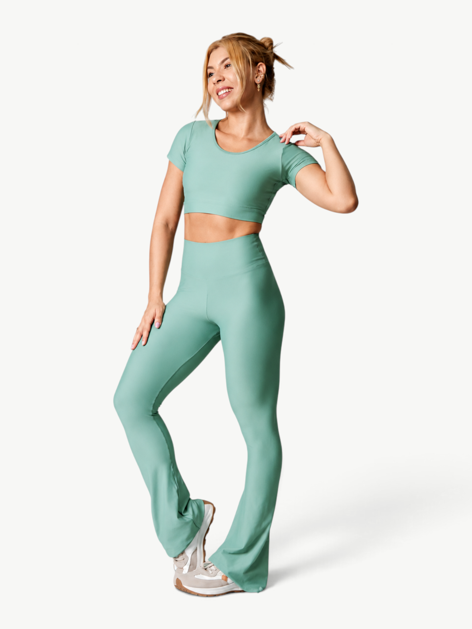 Model wearing a JM Brazilian Activewear sage green short-sleeve crop top and high-waisted flare pants set