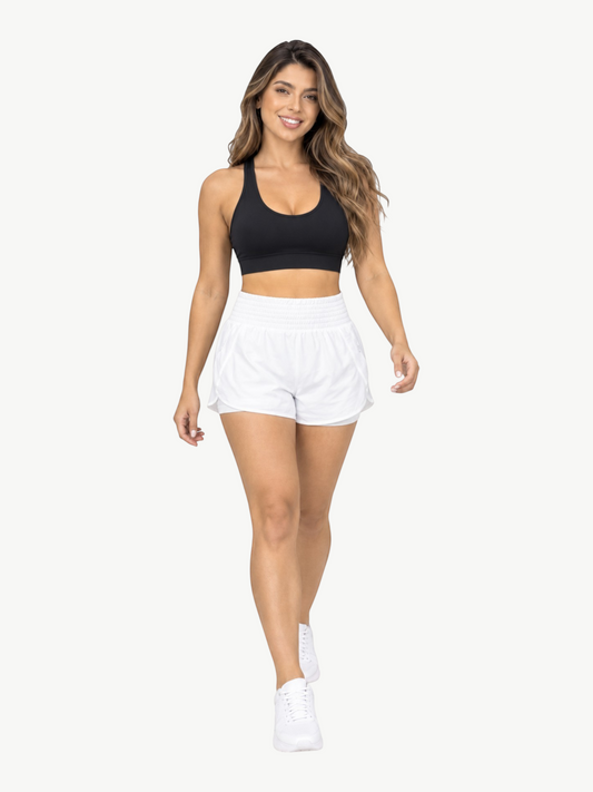 Model wearing JM Brazilian Activewear white 2-in-1 athletic shorts with a high waistband and black sports bra