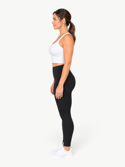 Model wearing a white JM Brazilian Activewear Dallas crop top with black leggings and white sneakers, side view.